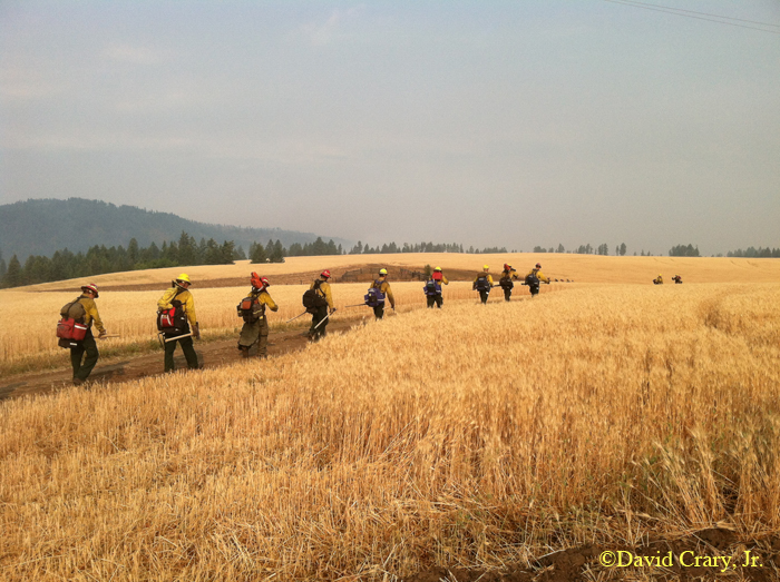 David Crary took this photo of his fire crew marching with their fire fighting tools and survival gear to do battle at the Incendiary Creek Fire in Idaho. If not careful, some of these brave professionals firefighters could suffer serious injury or worse.