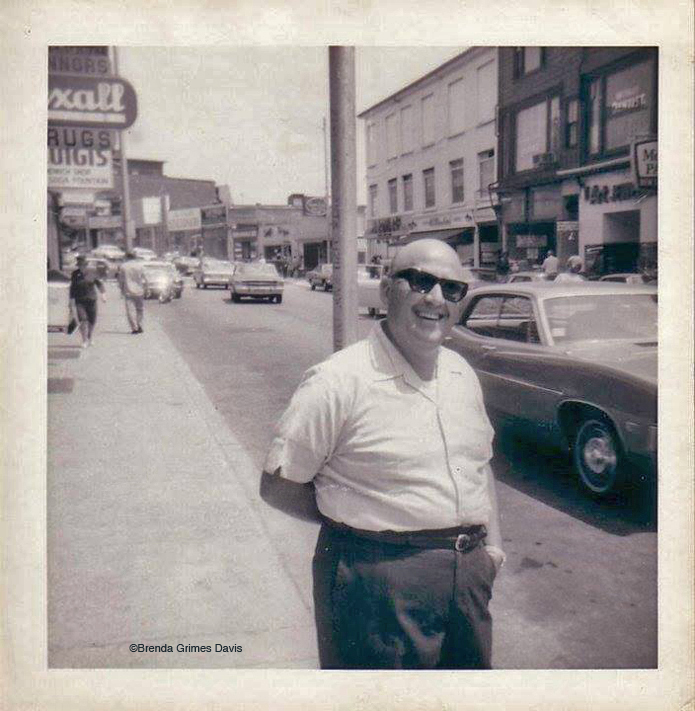 From Brenda Grimes Davis: "Fred...Here's a picture of Barney Marnoy who managed Benny Schred's fabric store...which was located where Passports (temporarily Village Pharmacy) is in the 1960s...he's standing just outside the door..I believe Benny was Barney's father-in-law." Notice the Rexall sign on the left. That was the original location of Connors Pharmacy on Main Street.