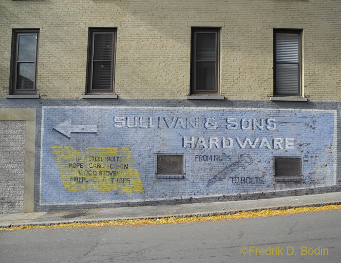 A sign painted on the wall of Gabriel's Antiques, on Center Street. Made to look old and weathered. "From Nuts to Bolts." HBO production.