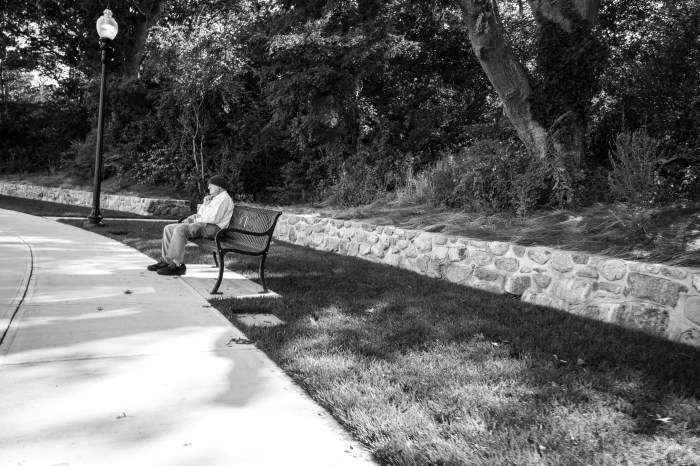 man on bench light pole